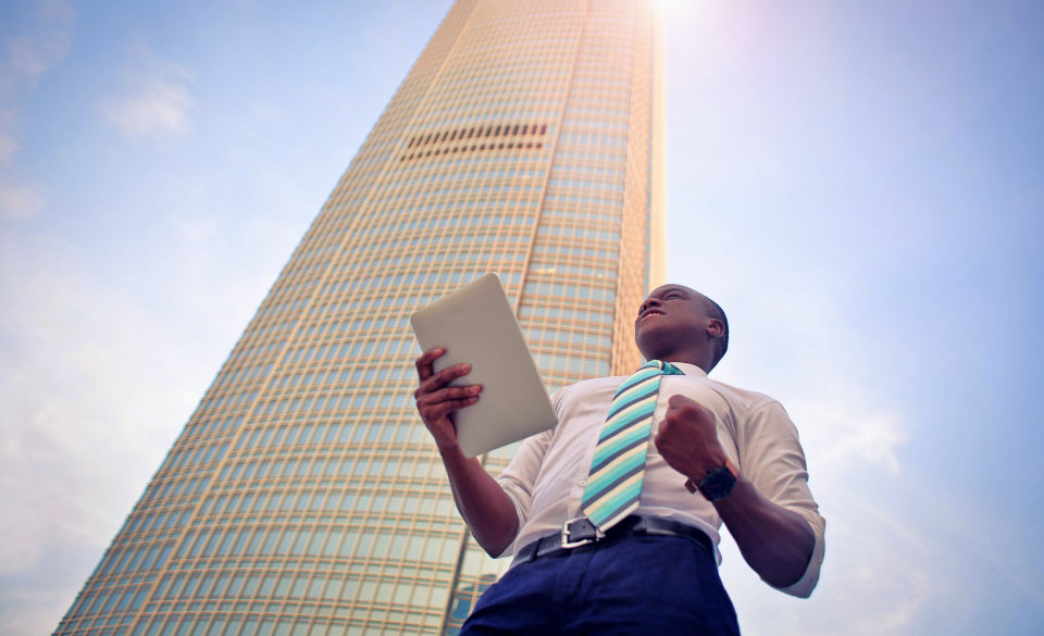 Man Standing outside Really Tall Building